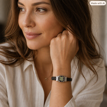 Load image into Gallery viewer, Female model wearing a braided leather bracelet with a silver four‑leaf clover charm, seated in warm natural light.
