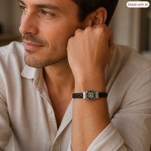 Load image into Gallery viewer, Male model wearing a braided leather bracelet with a silver four‑leaf clover charm, relaxed pose in soft warm lighting.