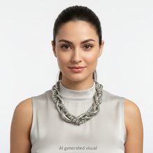 Load image into Gallery viewer, A woman with dark hair pulled back wears a chunky silver braided necklace with chunky coils, silver balls, and metal chains.   A small "AI generated visual" label is at the bottom of the image.

