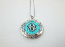 Load image into Gallery viewer, silver glow in the dark snowflake  locket necklace glowing blue. 