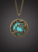 Load image into Gallery viewer, Glow in the dark gold brass fairytale locket necklace, glowing blue, close-up.