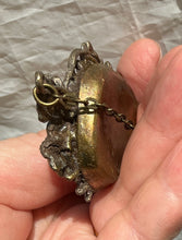 Load image into Gallery viewer, A close-up of a hand holding a pendant with copper back against a wrinkled light gray fabric background, close side view of pendant.