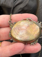 Load image into Gallery viewer, A close-up of a hand holding a pendant with copper back showing the smooth backing of the pendant.