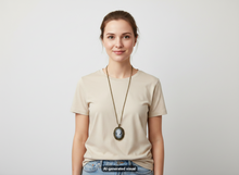 Load image into Gallery viewer, A woman wearing a beige crew-neck t-shirt and blue jeans, accessorized with a long bronze chain necklace featuring a antique bronze Victorian cameo watch necklace with photo locket pendant, standing against a light gray studio background.  A small 'AI-generated visual' label appears at the bottom.