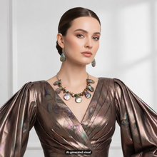 Load image into Gallery viewer, A woman wearing a metallic bronze wrap dress with iridescent shell-like embellishments on the bodice and sleeves, styled with a matching iridescent bronze shell and baroque pearl necklace and matching shell teardrop earrings against a bright white background.  A small "AI-generated visual" label is visible at the bottom. 