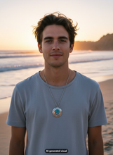 Load image into Gallery viewer, A man standing on a beach at sunset wearing a light blue-gray t-shirt and a silver glow in the dark mermaid and starfish locket necklace. The background shows the ocean waves and sandy shore under warm golden hour light.  A small "AI-generated visual" appears at the bottom.