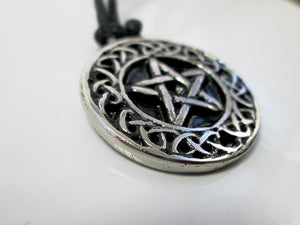 close up side view of Celtic pentacle pendant necklace, round pendant with black background, on black cord, for unisex teen or adult. (photo taken on a white background)