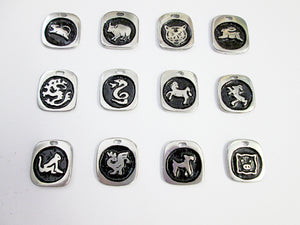 a display of 12 Chinese Zodiac Animal Sign Pendants with black background.  Top row from right to left: year of mouse, year of ox, year of tiger, year of rabbit.  Middle row from left to right: year of dragon, year of snake, year of horse, year of goat or sheep.  Bottom row from left to right: year of monkey, year or rooster, year of dog, year of pig.  (picture taken on a white background)
