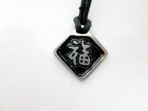 Chinese symbol of good luck pendant necklace, pendant with black background, on black cord.