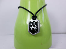 Load image into Gallery viewer, handmade pewter horse rider pendant necklace, pendant with black background, on black cord, for men or women. (photo taken of necklace on a green background)