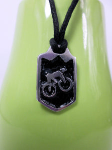 cycling pendant necklace, biker pendant necklace, pendant with black background, on black cord, for unisex teen or adult. (photo taken on a green background)