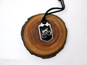 cycling pendant necklace, biker pendant necklace, pendant with black background, on black cord, for unisex teen or adult. (photo taken on a background with a piece of wood)
