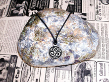 Load image into Gallery viewer, Celtic triskele pendant necklace, round pendant with black background, on black cord, for unisex teen or adult. (photo taken on a background with a rock)