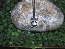 Load image into Gallery viewer, handmade pewter Canada Maple Leaf pendant necklace, pendant with black background, on black cord, for men or women (photo of necklace taken on a background with a piece of rock)