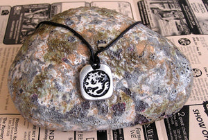 Year of the Dragon Chinese zodiac pendant necklace for unisex, squarish pendant with black background, cotton cord style. (picture taken on a background with a rock)