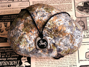 Year of the horse Chinese zodiac pendant necklace for unisex, squarish pendant with black background, cotton cord style. (picture taken on a background with a rock)