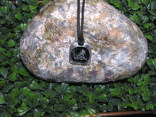 Load image into Gallery viewer, Year of the dragon Chinese zodiac pendant necklace for unisex, squarish pendant with black background, cotton cord style. (picture taken on a background with a rock)