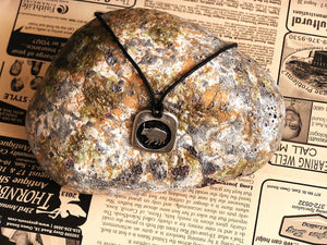 Year of the ox Chinese zodiac pendant necklace for unisex, squarish pendant with black background, cotton cord style. (picture taken on a background with a rock