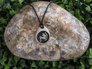 Sagittarius horoscope pendant necklace on black cord, teardrop pendant with black background, for man or woman. (picture taken on background with a rock