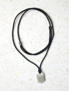 back view of golfer pendant on black cord, pendant polished to mirror finish.