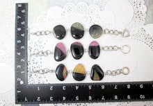 Load image into Gallery viewer, Three large agate stone statement bracelets displayed on a lace background with a black L‑shaped ruler for size reference, featuring green and black agates, pink and black agates, and brown and black agates.