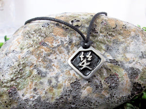 Kanji symbol for Laugh and Happiness pendant necklace, pendant with black background, on black cord.